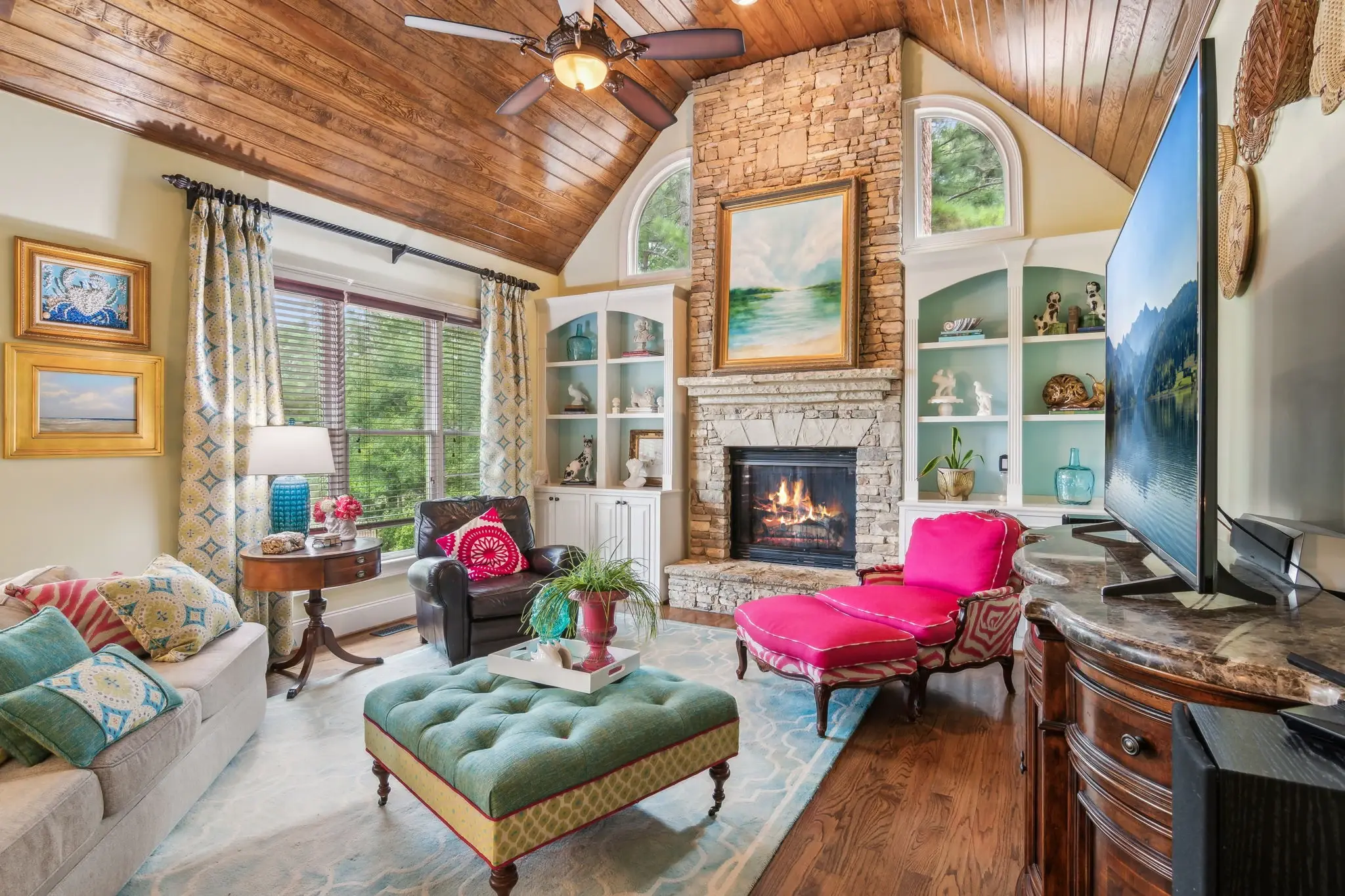 Colorful living room with a stone fireplace, patterned textiles, and a pink lounge chair
